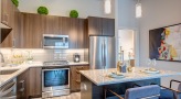 Spacious and well lit kitchen with stainless steel appliances and dark accents 