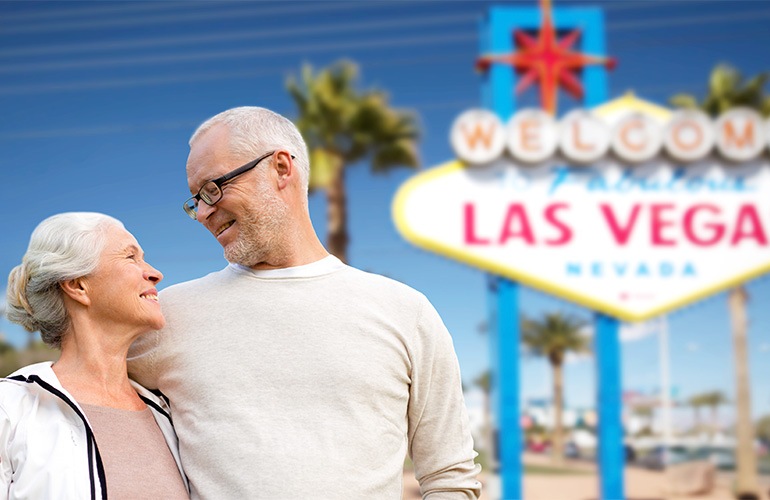 Close to the center of everything a couple standing in front of the Las Vegas sign