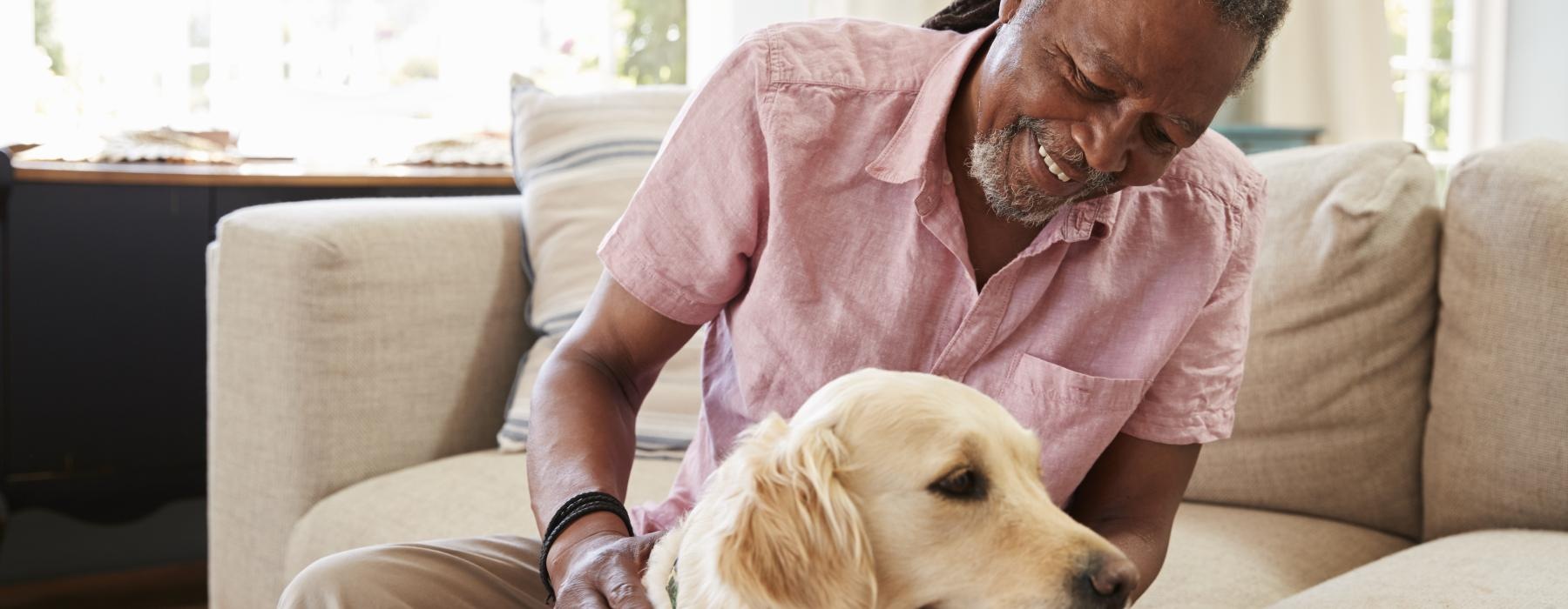 a man sitting on the couch petting a dog