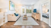 Spacious and well lit living room with wood floors and a large window