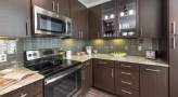 Spacious and well lit kitchen with stainless steel appliances and dark accents 