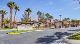 entrance to a parking lot with a sign and palm trees
