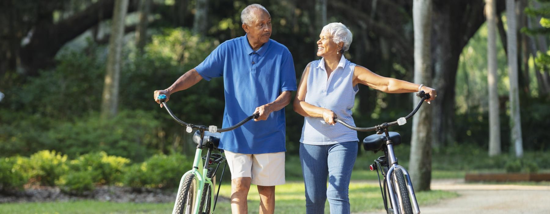 a couple walking with their bikes on a path outside