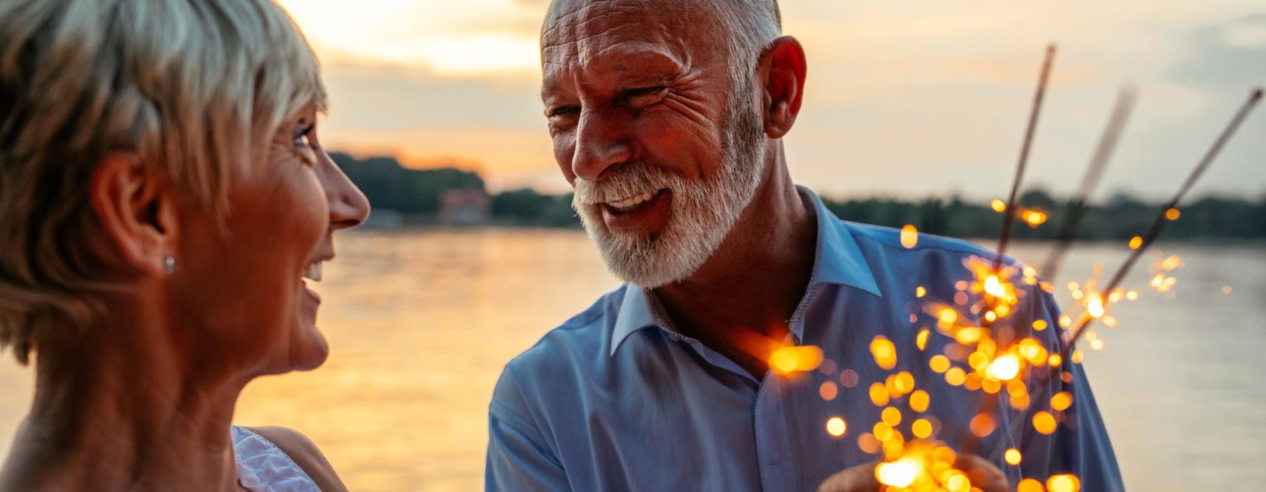 Couple with a lit sparkler by the water