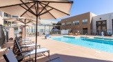 a pool in a courtyard with lounge chairs and umbrellas