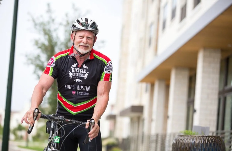 Senior adult man on a road bicycle standing next to a building.