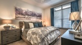 Large well lit bedroom with carpeted floors and a large window 