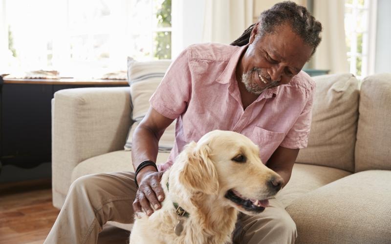 Guy sitting in a well lit living room with his dog