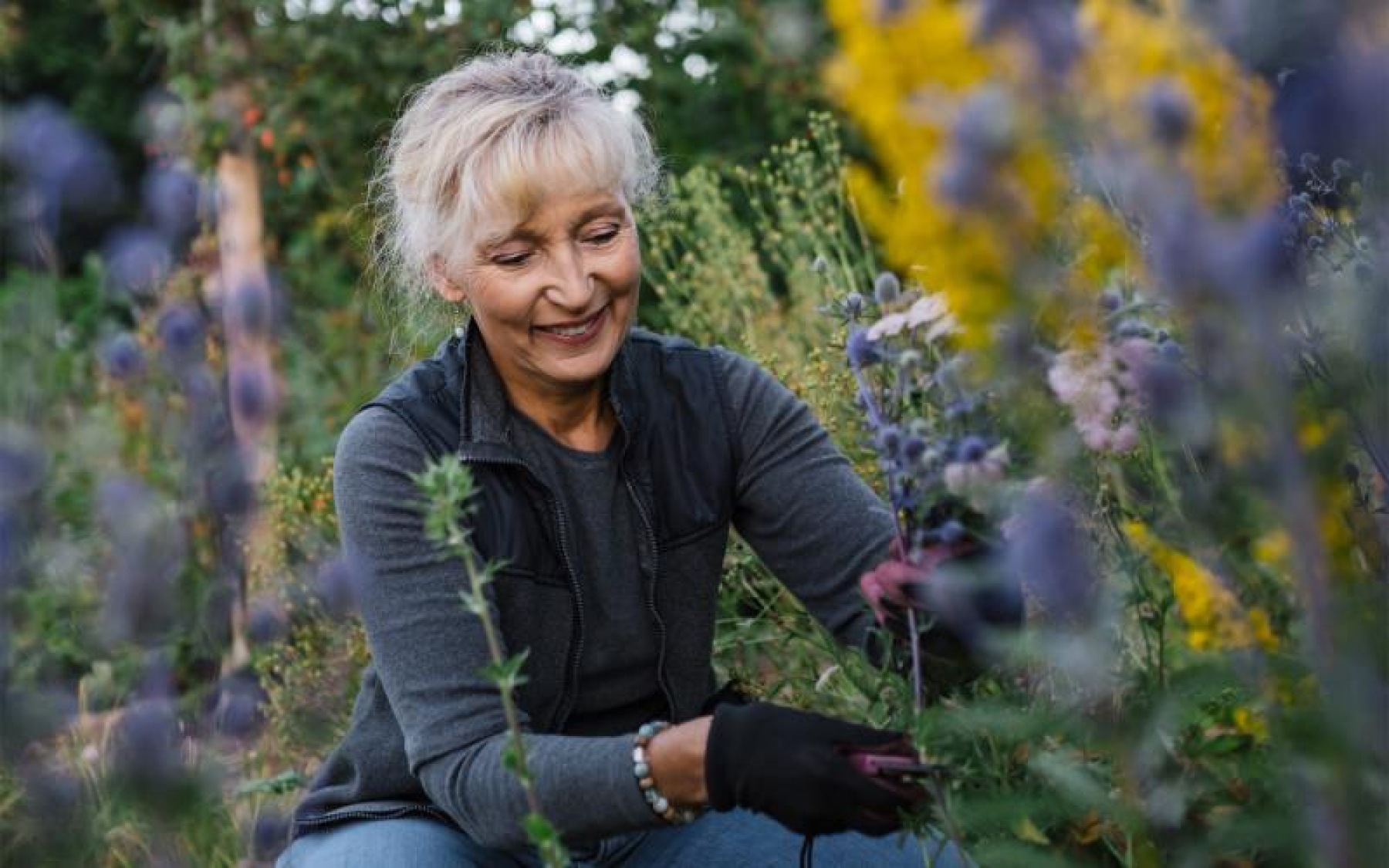 a woman kneeling in a field of plants
