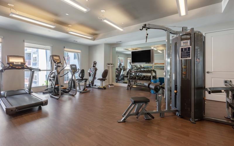 Large fitness center with ample machines and wood floors