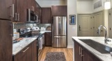 Spacious and well lit kitchen with stainless steel appliances and dark accents 