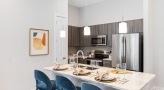 Spacious and well lit kitchen with stainless steel appliances and dark accents 