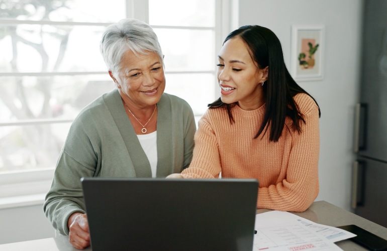 2 people smiling looking at a laptop
