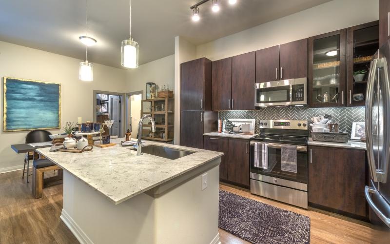 Spacious and well lit kitchen with wood floors and stainless steel appliances