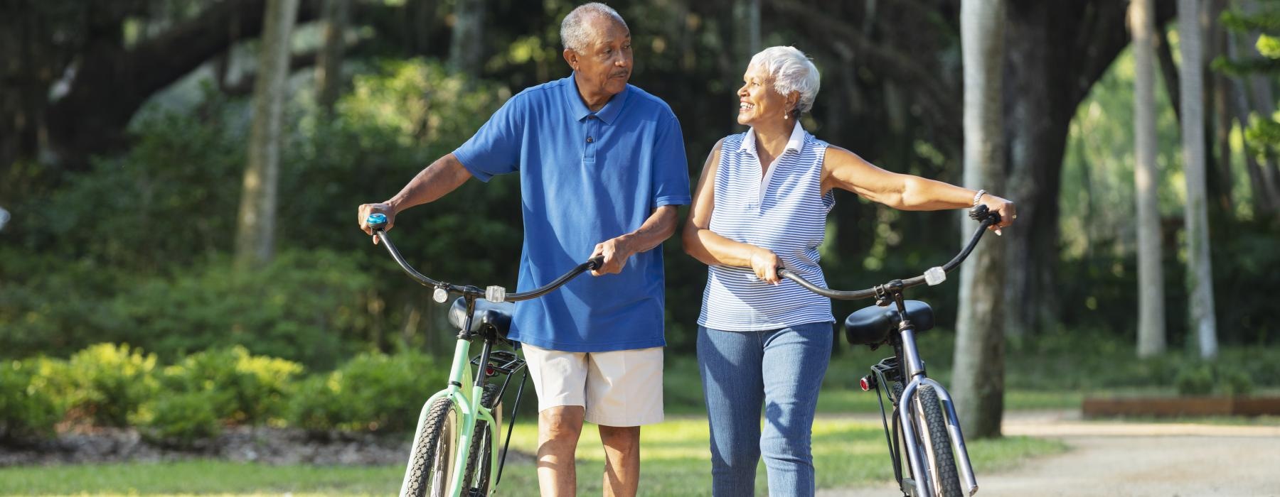 Couple walking with their bikes in a local park 