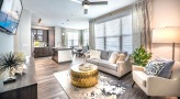 Spacious and well lit living room with wood floors and a large window