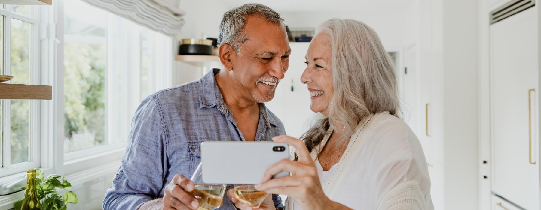 Couple standing in their kitchen smiling at their phone