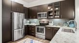 Spacious and well lit kitchen with stainless steel appliances and dark accents 