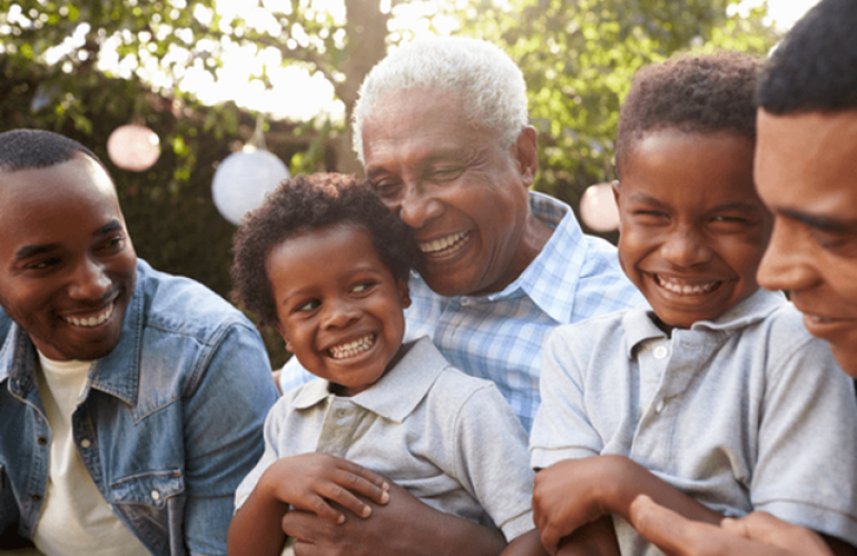 A grandfather hugging and sitting next to his grandchildren.