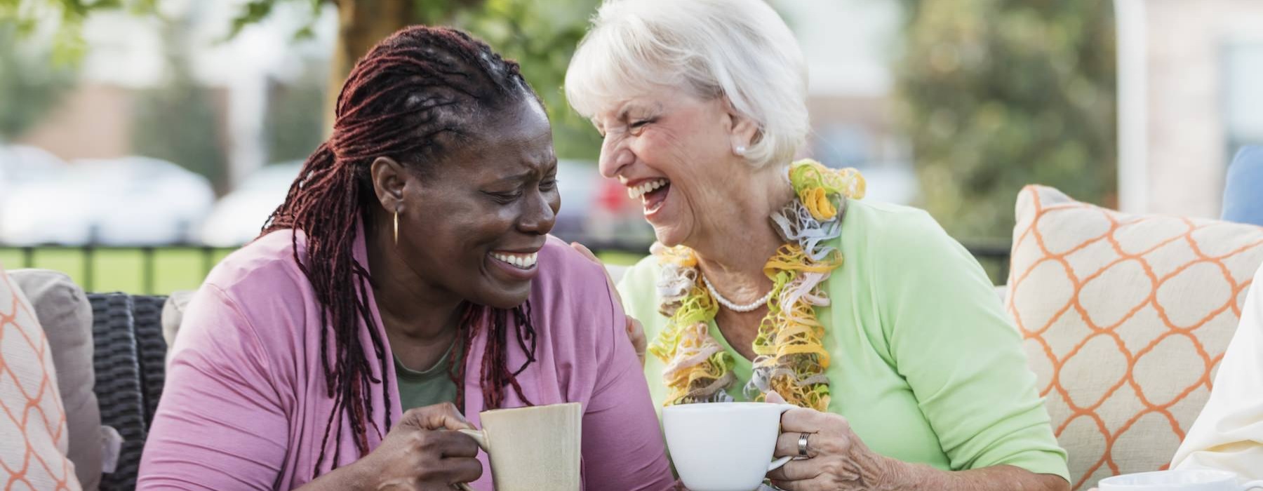 two women holding cups laughing