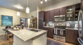 Spacious and well lit kitchen with stainless steel appliances and dark accents 