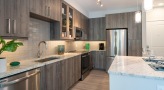 Spacious and well lit kitchen with stainless steel appliances and dark accents 