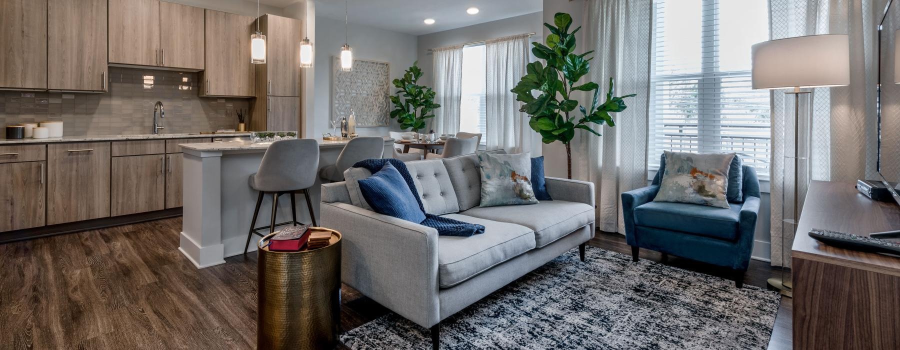 a living room with a couch and chairs open to kitchen