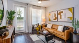 Spacious and well lit living room with wood floors and a large window