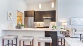 Spacious and well lit kitchen with stainless steel appliances and dark accents 