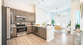 Spacious and well lit kitchen with stainless steel appliances and dark accents 