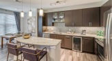 Spacious and well lit kitchen with stainless steel appliances and dark accents 