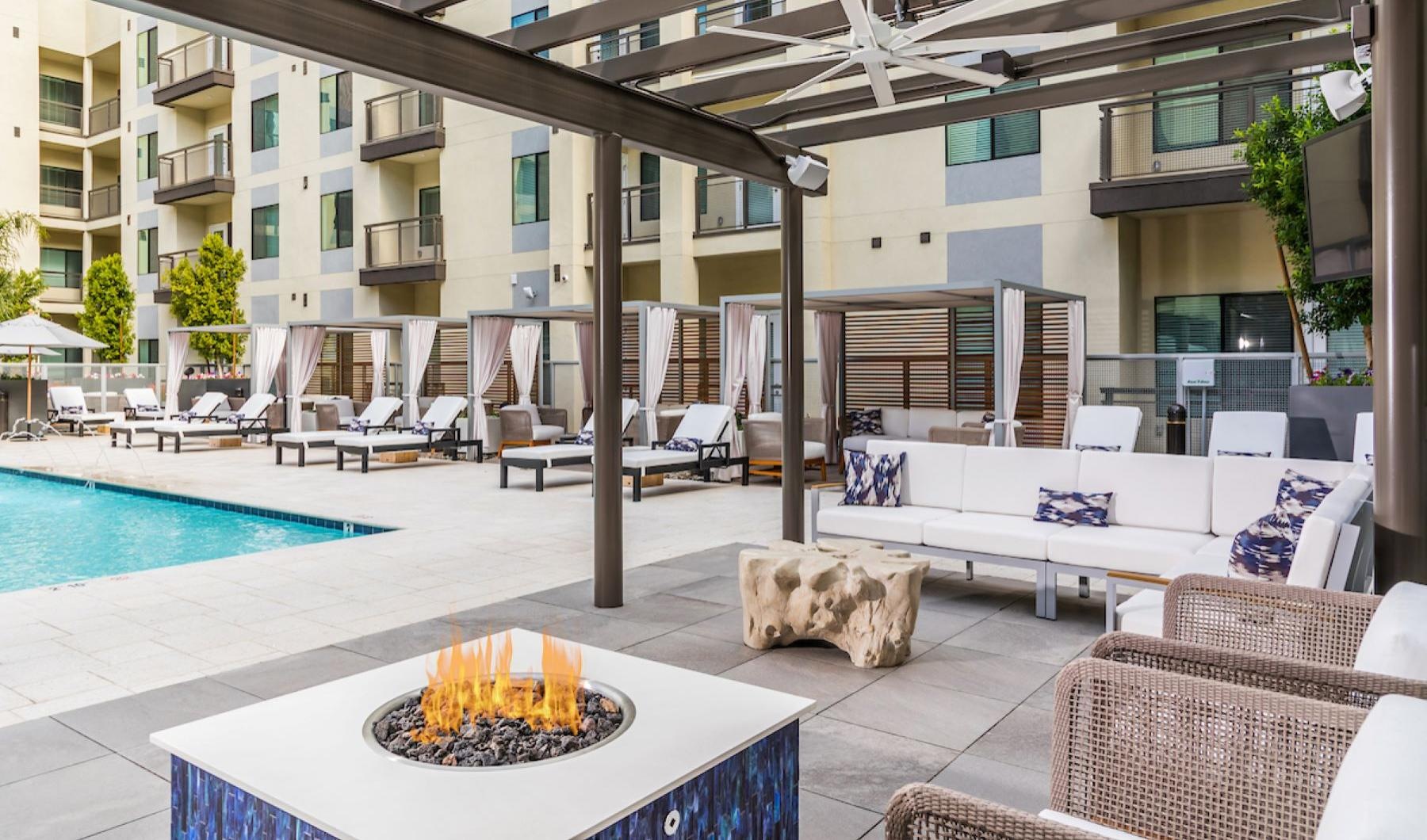 Relax and unwind poolside a large swimming pool with a fire pit and seating surrounding it