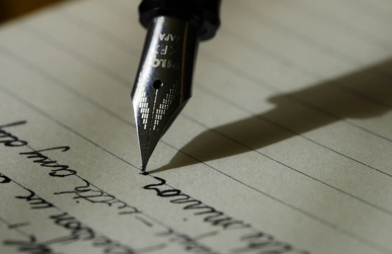 Close up of a quill pen writing on paper.