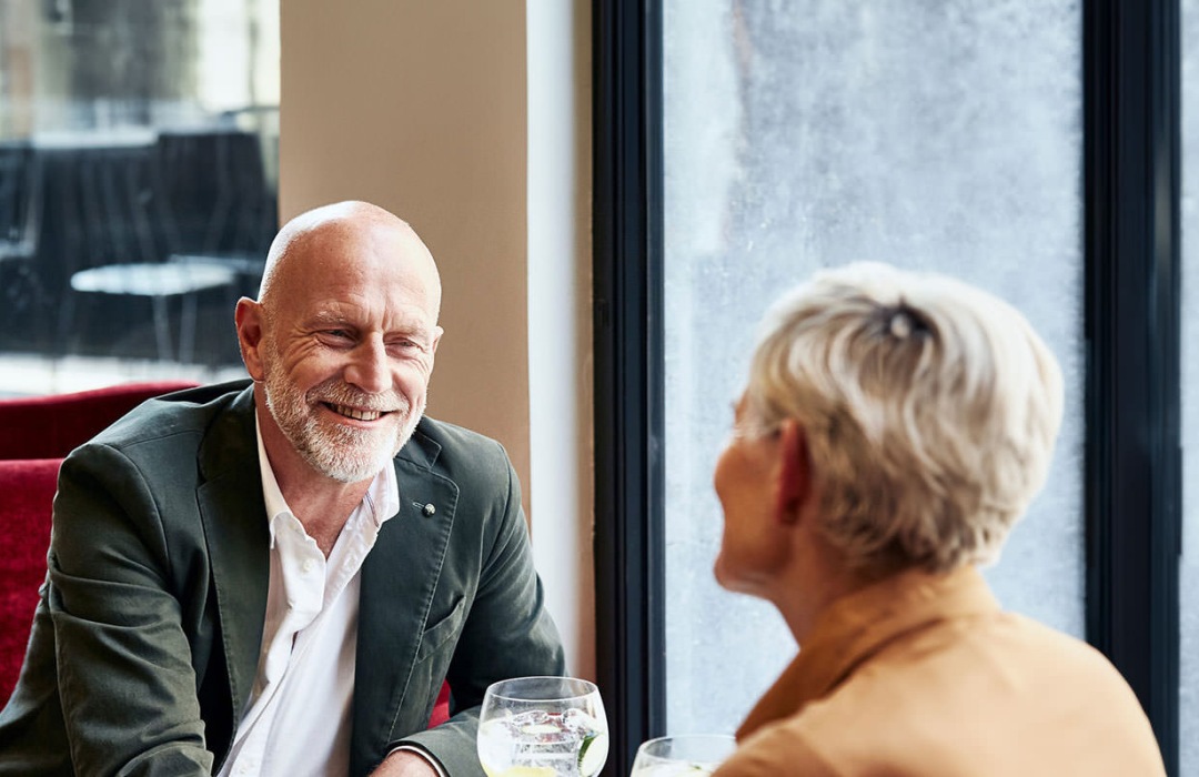 man and woman sitting at table sharing a drink together