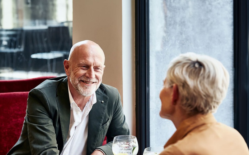 man and woman sitting at table sharing a drink together