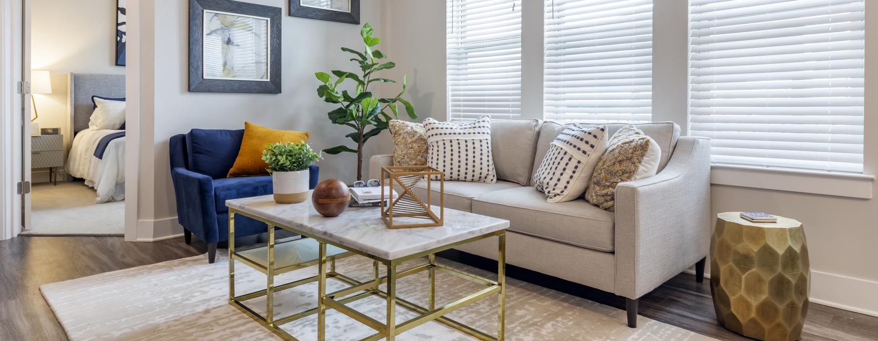 Spacious and well lit living room with wood floors and a large window with access to the kitchen