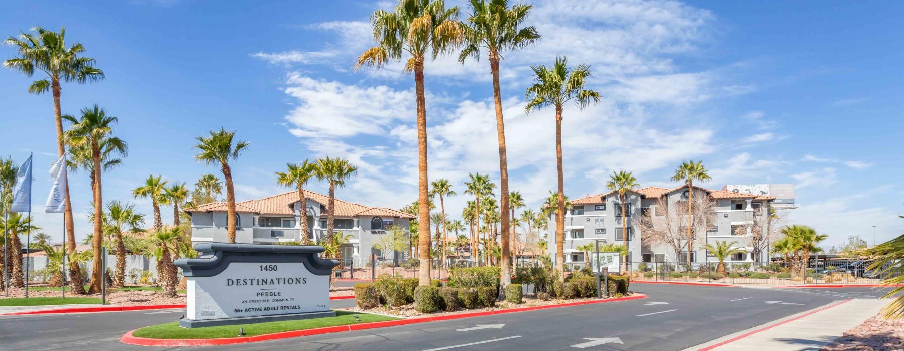 a sign leading into a parking lot with palm trees