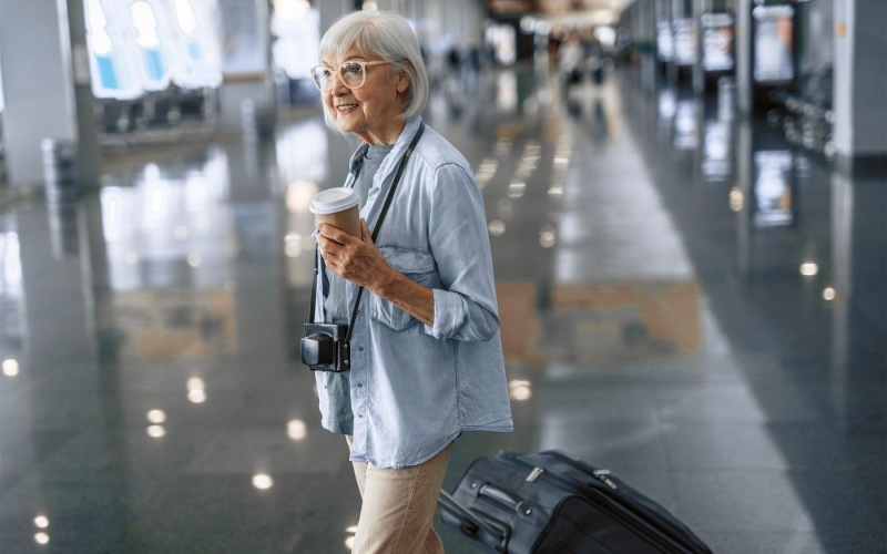 a woman with a coffee cup and luggage in an airport