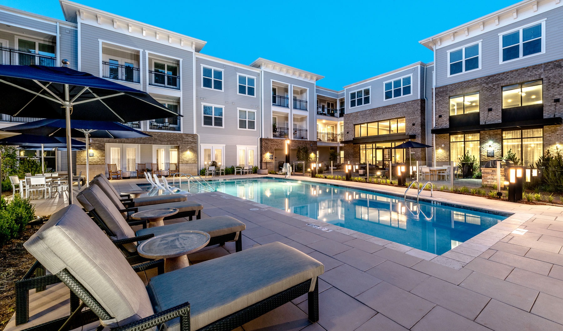 a swimming pool with lounge chairs and umbrellas next to it