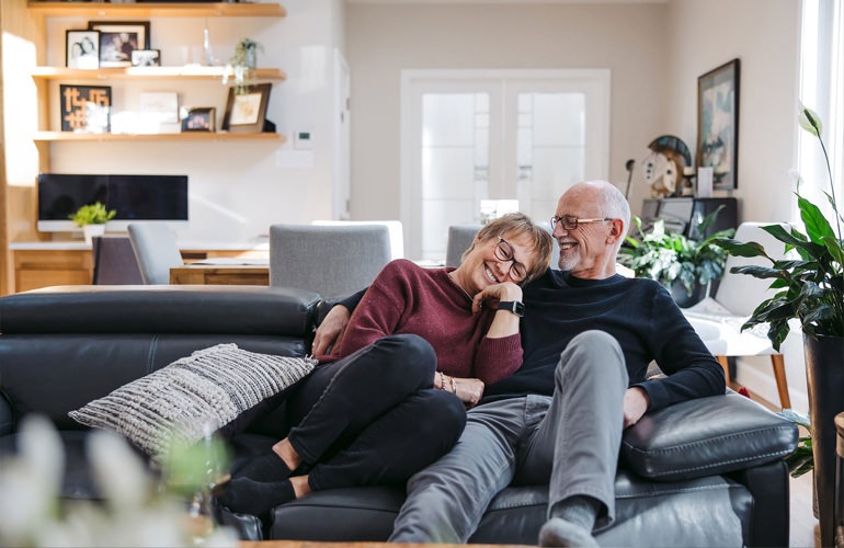 Senior adult couple laying on their couch and enjoying each other's company.