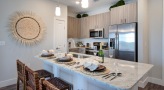 Spacious and well lit kitchen with stainless steel appliances and dark accents 