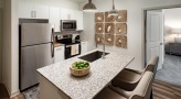 Spacious and well lit kitchen with stainless steel appliances and dark accents 