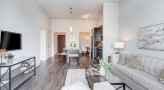 Spacious and well lit living room with wood floors and a large window