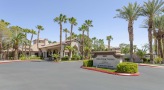 entrance to a parking lot with a sign and palm trees