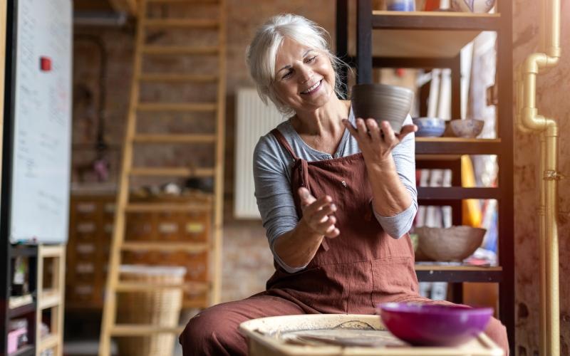 woman holds a bowl at a pottery wheel