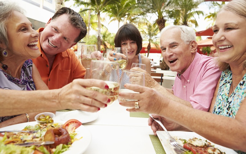 Nearby Activities & Attractions Friends saying cheers and tapping their glass around a table outside