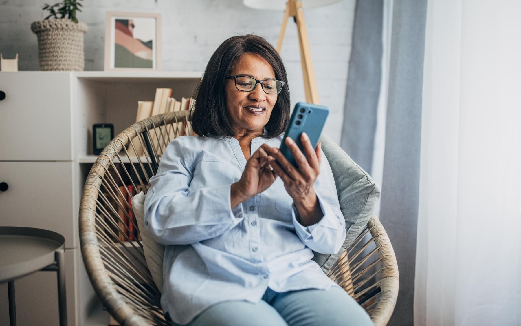 Lifestyle Woman sitting in front of a window smiling at her phone