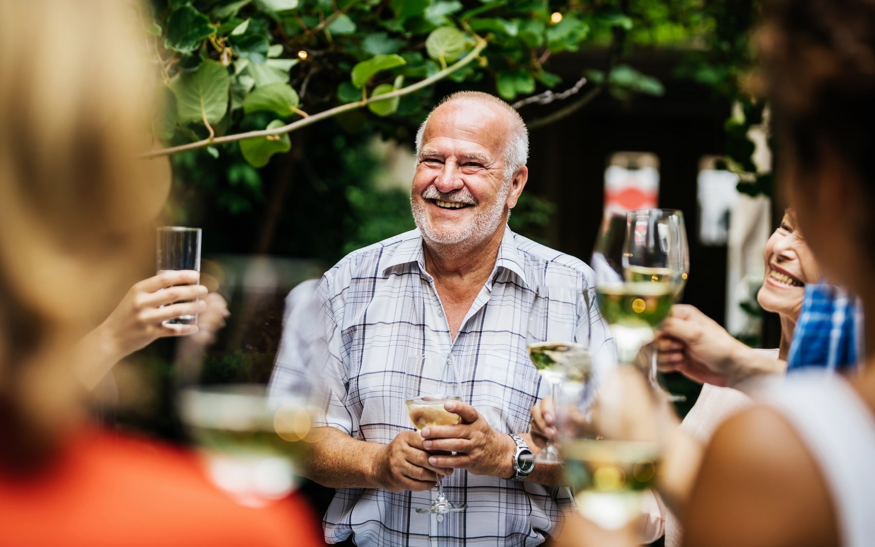 a man smiling holding a glass of wine with some friends