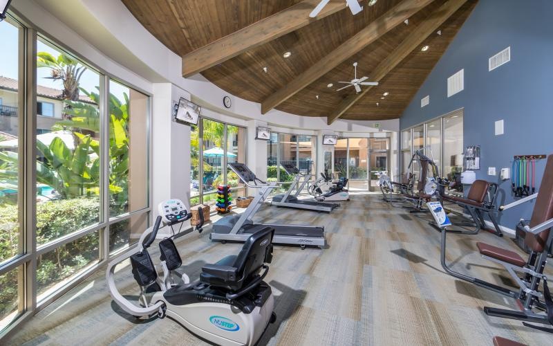 Large fitness center with ample machines and wood floors