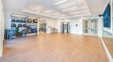 Large yoga room with wood floors and large mirrors 